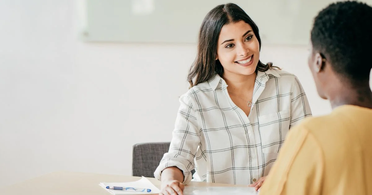 Hiring manager speaking with job candidate at desk