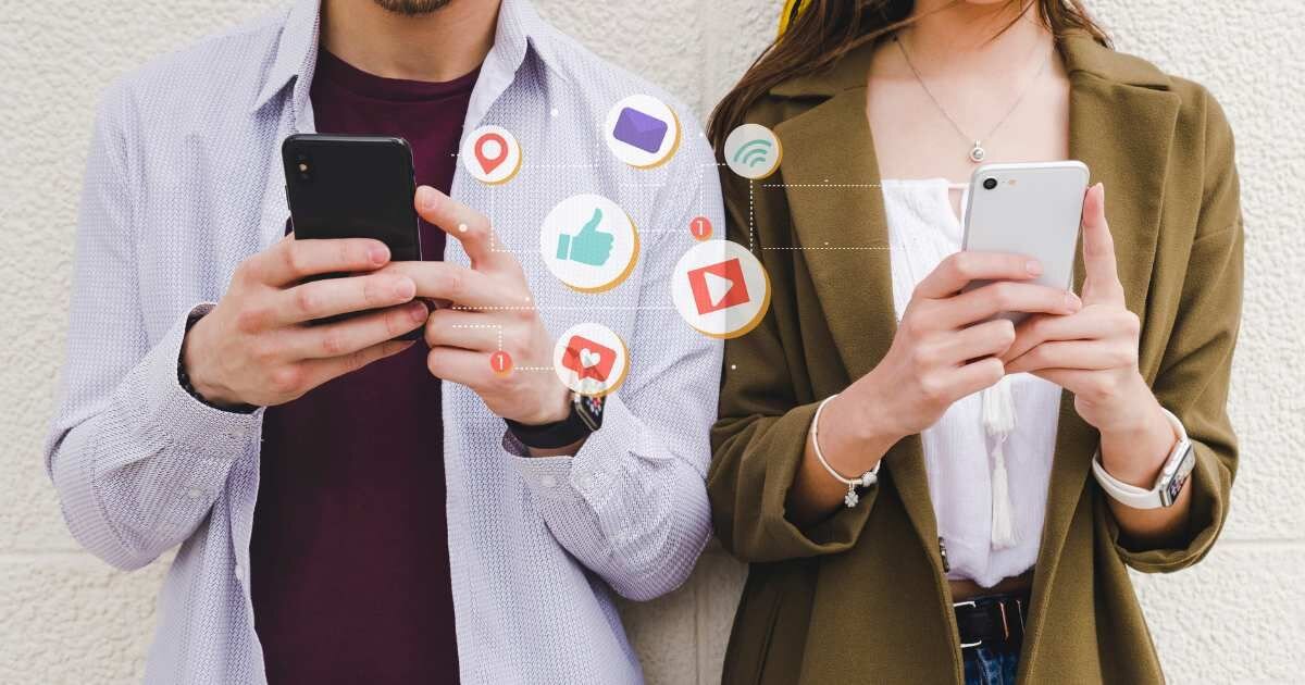 Social Media Interaction: "A man and woman using smartphones with social media icons floating between them.